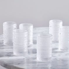 five clear glass cups sitting on top of a marble table