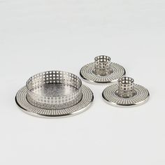 three silver plates and trays on a white surface