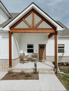 a white house with a wooden porch in the front yard and attached to a garage