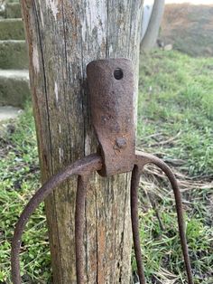 an old rusted metal hook attached to a wooden pole