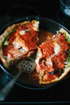 two pieces of deep dish pizza in a skillet with a spatula on the side