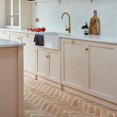 a kitchen with pink cabinets and marble counter tops, gold faucets and brass pulls