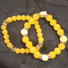 Elastic Stretches To Fit Most Any Wrist. Two Pretty Yellow Beaded Bracelets With Metal Bead Separators With Cz's. One Bracelet Has 4 Light Yellow Flat Round Bead Accents And The Other Has Four Faceted Yellow Sparkly Bead Accents. Great Summer Color! Stones Are Possibly Yellow Agate Or Yellow Jade Semi Precious Stones, Not Sure Which. One Bracelet The Stones Are Larger Than The Other. Handmade Handcrafted Hand Made Hand-Made Artisan #1 Yellow Bead Bracelet Ideas, Casual Round Yellow Jewelry, Casual Yellow Round Jewelry, Handmade Yellow Stretch Bracelet, Handmade Trendy Yellow Bracelets, Trendy Handmade Yellow Bracelets, Elegant Yellow Adjustable Beaded Bracelets, Adjustable Yellow Round Bracelets, Elegant Yellow Stretch Bracelet With Round Beads