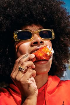 a woman wearing sunglasses eating a piece of pizza