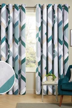 a living room with blue and white curtains, a green chair, and a rug