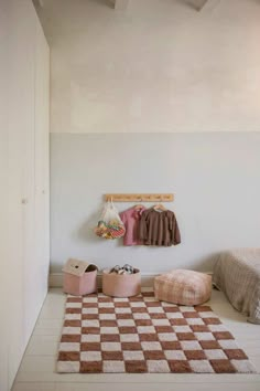 a bedroom with a checkered rug and two small pink stools on the floor