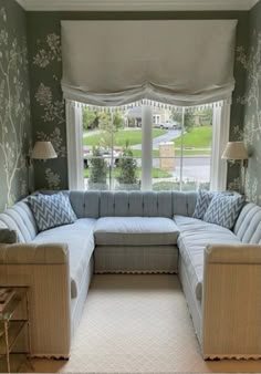 a living room filled with furniture next to a large window covered in windowsills