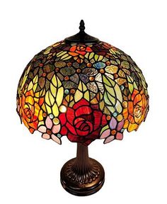 a lamp that is sitting on top of a wooden stand with a rose design on it