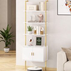 a living room with a white couch and shelving unit next to a painting on the wall