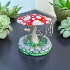 a small red mushroom sitting on top of a table next to some succulents