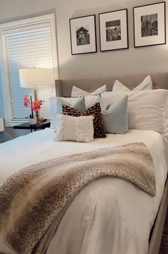 a bed with white sheets and pillows in a bedroom next to two pictures on the wall