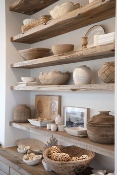 some shelves with bowls, plates and other items on them in a room that has white walls