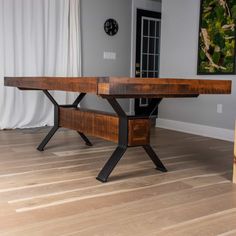 a wooden table sitting on top of a hard wood floor next to a wall mounted clock