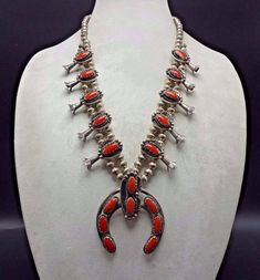 "VINTAGE NAVAJO SQUASH BLOSSOM NECKLACE DESCRIPTION: This stunning necklace features 18 oval cabochons of old red Mediterranean coral. The gemstones are secure in scalloped bezel, on a foundation of heavy gauge vintage sterling silver. Each blossom is framed with an applied leaf, applied raindrops, and a sterling silver swirl. This magnificent necklace will be a valuable addition to your collection of fine vintage Native American jewelry. MEASUREMENTS: Necklace measures 26\" end to end Naja meas