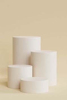 three white vases sitting next to each other on a beige background, one is empty