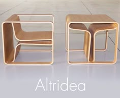 two wooden chairs sitting next to each other on top of a tile floor in front of a white wall