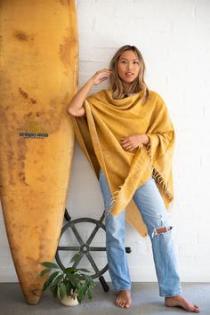 This honey-hued poncho is handwoven in Nepal on majestic wooden looms using a soft, unique yarn and finished with perfectly twisted tassels. Sewn in Western Australia, this piece is perfect for chilly mornings or cool beach evenings. It's easy to style this poncho. Wear it with the v-neck at the front or diagonal for a different look. One size fits most. Approximate size overall is 30 x 74 inches. Wash by hand in cold water and dry with care. One Size Beach Shawl With Fringe, Cozy One Size Poncho For Beach, Cozy Fall Poncho For Beach, Yellow Bohemian One Size Poncho, Yellow Bohemian One-size Poncho, Bohemian Yellow Poncho One Size, Yellow Bohemian Poncho One Size, Yellow Bohemian Poncho For Fall, Bohemian One-size Handwoven Cape