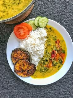 a white plate topped with rice and veggies next to a bowl of soup