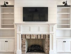 a living room with white bookcases and a tv mounted on the wall above a fireplace