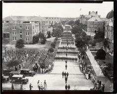 black and white photograph of people walking in front of an old building with many fountains