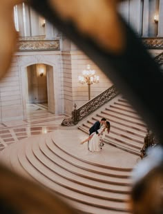 two people are standing on the stairs in an ornate building with chandeliers and lights