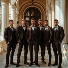 a group of men standing next to each other wearing suits and bow ties in front of a building