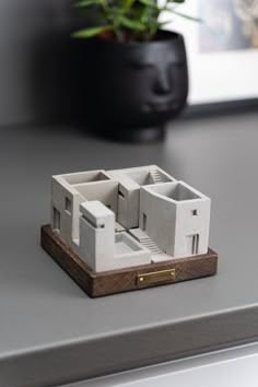 a model of a house sitting on top of a table next to a potted plant