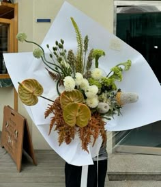 a person holding a bouquet of flowers in front of a building