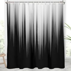 a black and white shower curtain hanging in front of a bathroom window with a chair