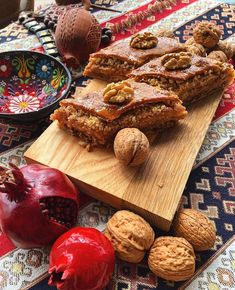 some food is laying out on a wooden cutting board next to other foods and nuts