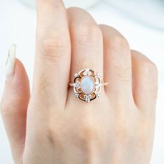 The "Ophelia" ring is an opulent masterpiece, featuring an oval-cut natural opal as its centerpiece, set in 18k rose gold. The intricate design surrounds the luminous opal with sparkling moissanite stones, creating a radiant floral motif. This vintage-inspired yet statement-making ring exudes both elegance and drama, perfect for those seeking a bold yet sophisticated look. "Ophelia" captures the ethereal beauty of nature and the allure of timeless luxury. Flora Ring Design - October Birthstone Ring MAIN STONE Stone: Natural Opal Shape: Oval Cut Color: blue white Measurements: 5x7mm SIDE STONES Moissanite:Round Cut:1.5mm--4 2.0mm--2 2.5mm--2 Marquise Cut:2.0*4.0mm--2 BAND Style: Cluster / Flora Ring / Vintage Ring Material:14k Gold: yellow, white, rose18k Gold: yellow, white, roseOther Meta Elegant Moonstone Ring With Gemstone Accents For Formal Occasions, Elegant Moonstone Ring With Gemstone Accents For Formal Events, Elegant Formal Moonstone Ring With Gemstone Accents, Exquisite Opal Ring For Gift, Exquisite Opal Ring Gift, Formal Oval Opal Ring With Gemstone Accents, Luxury Oval Opal Ring For Anniversary, Exquisite Oval Opal Ring, Luxury Rose Gold Opal Gemstone Ring