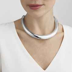 The ultimate in sculptural Scandinavian jewellery, the striking Aura neck ring makes a dramatic statement. Superb craftsmanship is combined with sensuous contemporary design to create a single organic ring of sterling silver that wraps around the neck and sits perfectly on the collarbone to frame the wearer’s face. With a background in textile and interior design, Danish born Anne Ammitzbøll has an unconventional approach to creating jewellery. Her work for Georg Jensen is characterised by bold Luxury Modern Sterling Silver Necklace, Silver Modernist Necklaces For Formal Occasions, Modern Silver Necklace, Modern Silver Geometric Necklace, Scandinavian Jewelry Georg Jensen, Neck Rings, Modernist Polished Silver Necklaces, Neck Ring, Scandinavian Jewelry