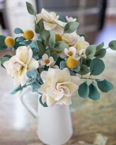 a white vase filled with flowers on top of a table