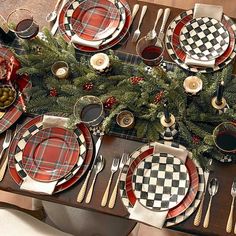 a christmas table setting with red and black plaid plates, place settings, silverware