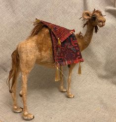 a stuffed camel with a red and black blanket on it's back is shown