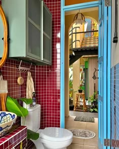 a bathroom with red and blue tiles on the walls, toilet and sink in it