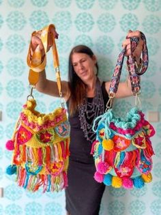 a woman holding two colorful purses in her hands