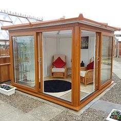 a small wooden structure with glass doors on the inside and outside, in front of a patio area