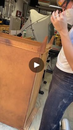 a woman standing next to a wooden cabinet in a room with other furniture and tools