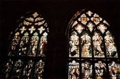 two very large stained glass windows in a building with people on it's sides