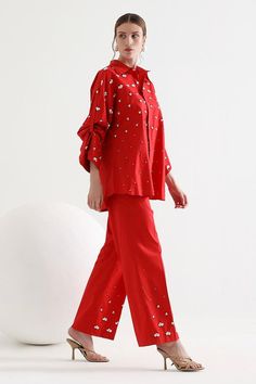 Red shirt featuring floral embroidery, asymmetric sleeves, and a shirt collar. Paired with matching embroidered pants., Fit: Relaxed Embellished Cotton Sets For Eid, Chic Embroidered Sets For Workwear, Red Cotton Sets With Mirror Work, Embellished Long Sleeve Workwear Sets, Long Sleeve Embellished Sets For Workwear, Embellished Long Sleeve Pant Set For Spring, Embellished Long Sleeve Sets For Workwear, Spring Embellished Long Sleeve Pant Set, Festive Embroidered Workwear Pant Set