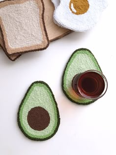 an avocado shaped coaster next to two pieces of bread and a cup of coffee