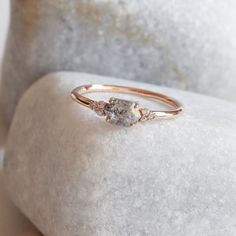 a close up of a diamond ring on top of a white marble slab with a rock in the background