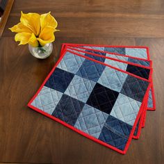 three placemats and a vase with yellow flowers on a wooden table