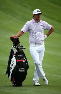 a man with a golf bag walking across a green field