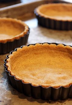 four pie pans sitting on top of a baking sheet