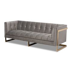 a gray velvet couch with gold legs