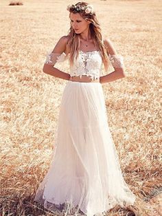 a woman standing in a field wearing a white dress and headpiece with flowers on it