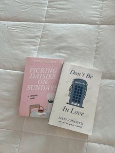 two books sitting on top of a bed next to each other in front of a white quilt