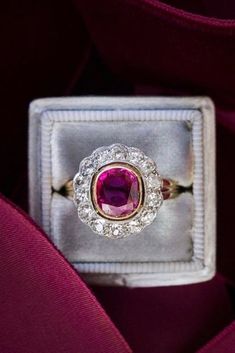 an engagement ring with a large pink stone surrounded by small white diamonds in a velvet box